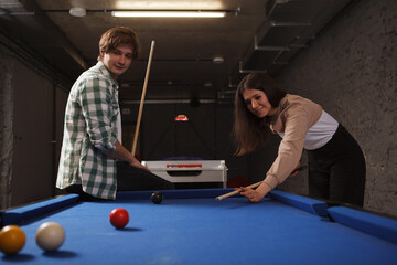Fototapeta premium Friends enjoying playing billiard on a pool table