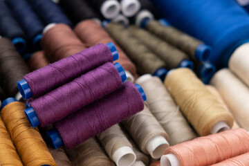 Multi-colored sewing threads laid out in a row. Bright background. Purpul