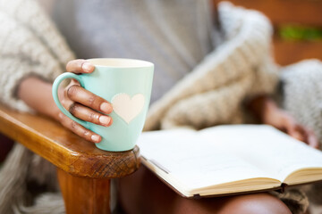 Tea and a good book. What more do you need. Cropped shot of a woman relaxing with a book and a cup of coffee.