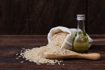 Rice bran oil extract with paddy and brown rice on wood table background.