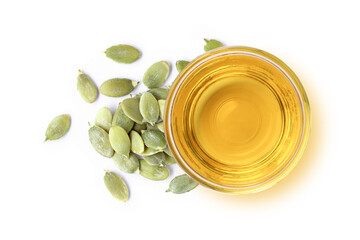Pumpkin seed oil in glass bowl and dry pumpkin seed isolated on wooden table background. Top view....