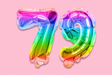 Rainbow foil balloon number, digit seventy nine on a pink background. Birthday greeting card with...