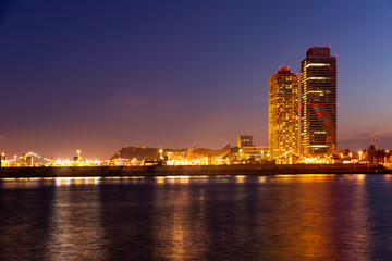 Naklejka premium Evening view of Barcelona with illuminated buildings from Mediterranean sea