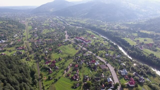 Stunning aerial shot of a small town near a river in the Carpathian mountains in summer