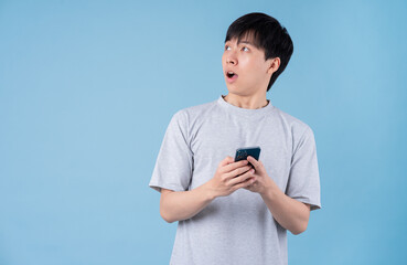 Young Asian man using smartphone on blue background