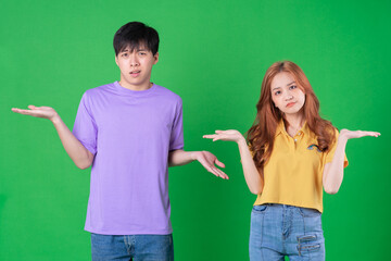 Young Asian couple posing on green background