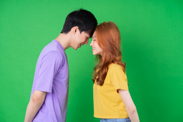 Young Asian couple posing on green background