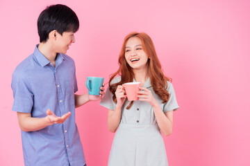 Young Asian couple drink tea on pink background