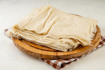 Thin layers of filo dough on a light table sprinkled with flour.