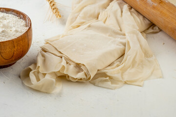 Phyllo dough lies on a light table. Raw filo dough.