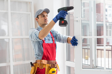 handyman adjusting white pvc plastic window indoors. worker using screwdriver to repair upvc...