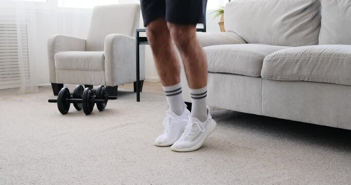 Low section of man doing jumping jack exercise at home