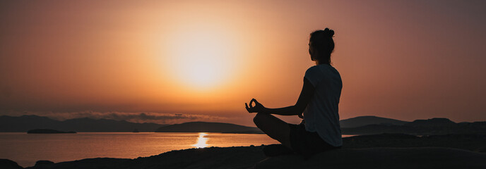 woman in white doing yoga and meditating by the sea