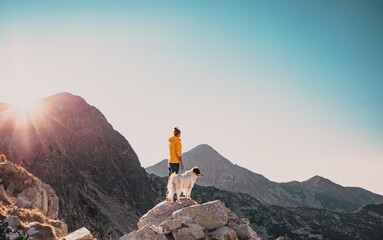 woman with white dog sitting on mountain top in summer landscape slow travel and freedom concept - Powered by Adobe