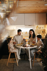 A family of 4 people sits at a table and prays before eating