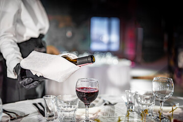 waiter pouring red wine into a glass in cafe or restaurant. catering 
