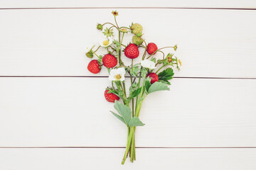 Bunch of strawberries with flowers, strawberry bouquet on white wooden background