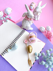 Pink Desktop. Notebook on the table with easter decorations. Frame border flat lay copy space top view. 