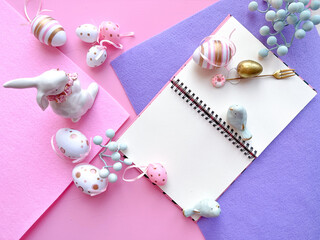 Pink Desktop. Notebook on the table with easter decorations. Frame border flat lay copy space top view. 