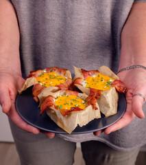 Frühstücksmuffins mit Speck und Ei , serviert von einer Frau
