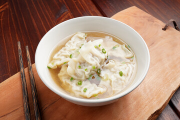 Pork dumplings boiled in clear water in a ceramic cup on a wooden table