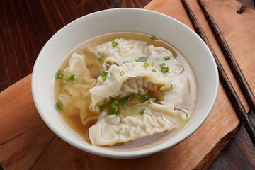 Pork dumplings boiled in clear water in a ceramic cup on a wooden table