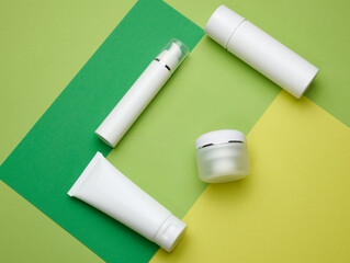 jar, bottle and empty white plastic tubes for cosmetics on a green background. Packaging for cream, gel, serum, advertising and product promotion