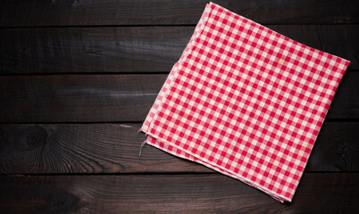 Obraz premium folded red and white cotton kitchen napkin on a wooden brown background, top view, copy space