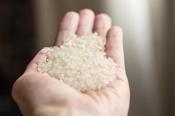 Hand with many grains of uncooked rice