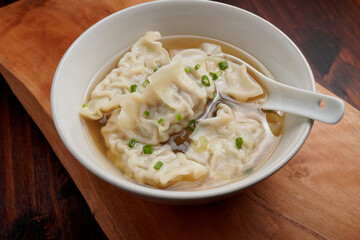 Pork dumplings boiled in clear water in a ceramic cup on a wooden table