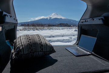 車中でのリモートワーク（ワーケーション）イメージ　積雪した富士山の麓で　remote working in the car at the foot of mount Fuji in winter