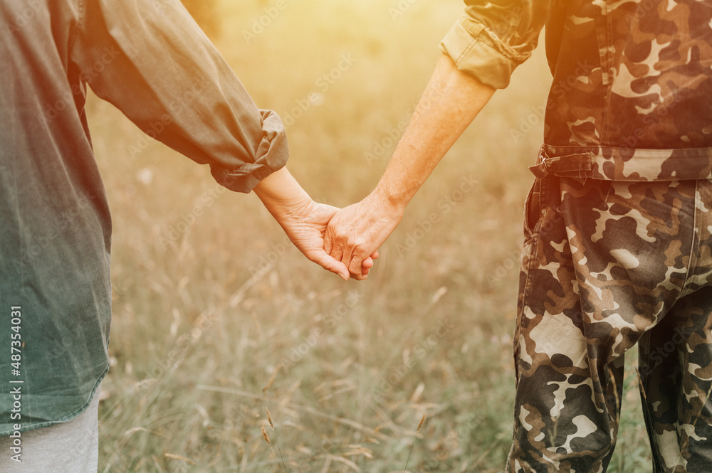 Wall mural happy senior couple holding hands. hands of man and woman hold each other. romance and love and support in elderly family. faceless husband and wife travel together in nature. countryside life. flare