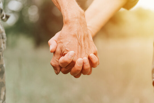 happy senior couple holding hands. hands of man and woman hold each other. romance and love and support in elderly family. faceless husband and wife travel together in nature. countryside life. flare