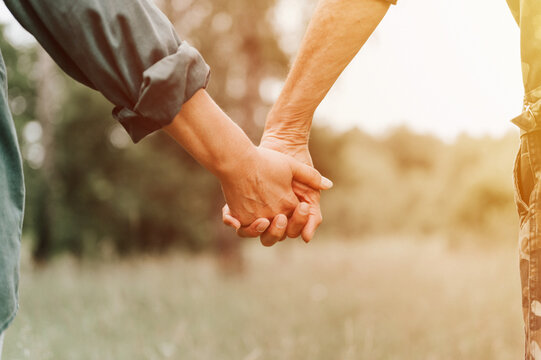 happy senior couple holding hands. hands of man and woman hold each other. romance and love and support in elderly family. faceless husband and wife travel together in nature. countryside life. flare