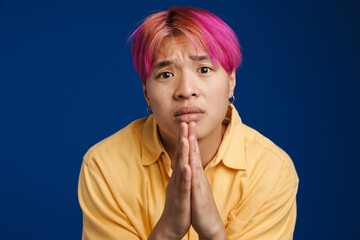 Asian boy with pink hair frowning while payer gesture