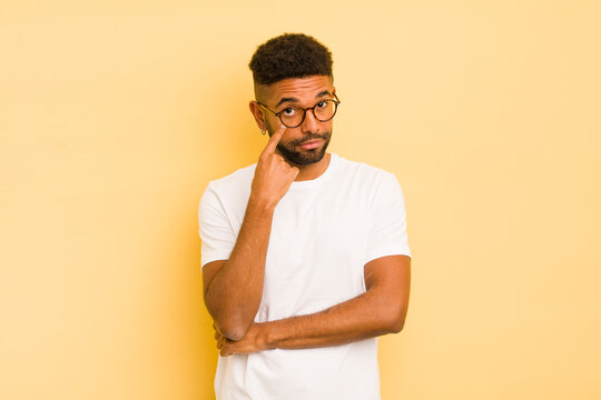 young afro man keeping an eye on you, not trusting, watching and staying alert and vigilant