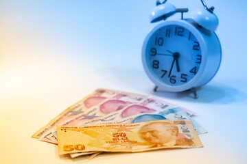 50, 100 and 200 Turkish banknotes and alarm clock on colorful background. Time is money concept.