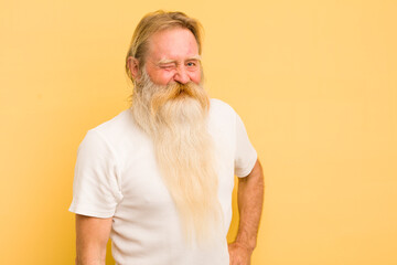 senior cool bearded man looking happy and friendly, smiling and winking an eye at you with a...