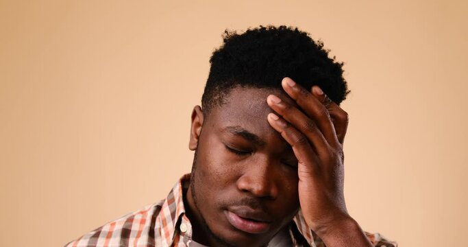 Frustrated man saying no by shaking his head over beige background