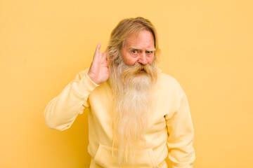 senior cool bearded man looking serious and curious, listening, trying to hear a secret...