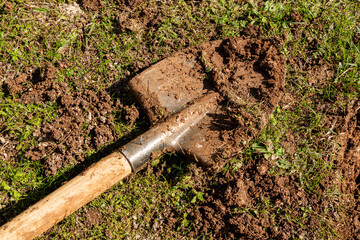 Used farming shovel with soil on it. Gardening, spring, agriculture concept.