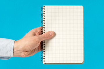 Man hand holding a notebook with square grid