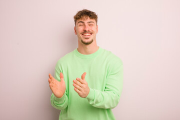 young cool man feeling happy and successful, smiling and clapping hands, saying congratulations...