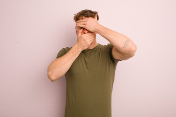 young cool man covering face with both hands saying no to the camera! refusing pictures or...