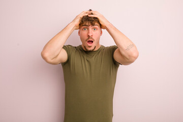 young cool man feeling horrified and shocked, raising hands to head and panicking at a mistake