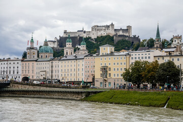 Fototapeta na wymiar Salzburg, Austria, 28 August 2021: old medieval castle on hill, Hohensalzburg Fortress, embankment panorama of river Salzach, renaissance and baroque houses, Facade of stone building at summer day