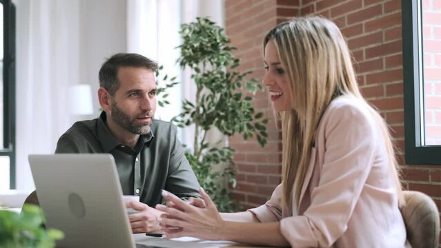 Video of smart business people working together with laptop while talking in the coworking place.