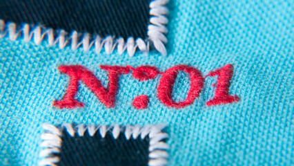 Número 01 bordado con hilo rojo en tejido de algodón azul