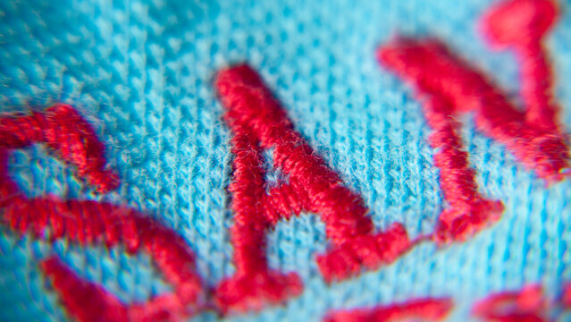 Letra A bordada con hilo rojo en tejido de algodón azul