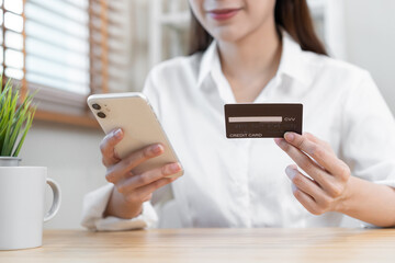 Internet banking, Online shopping at home, happy asian young woman, girl hand in holding credit card, using smartphone, mobile spending money with purchase, pay on store at home. Shopaholic e-commerce